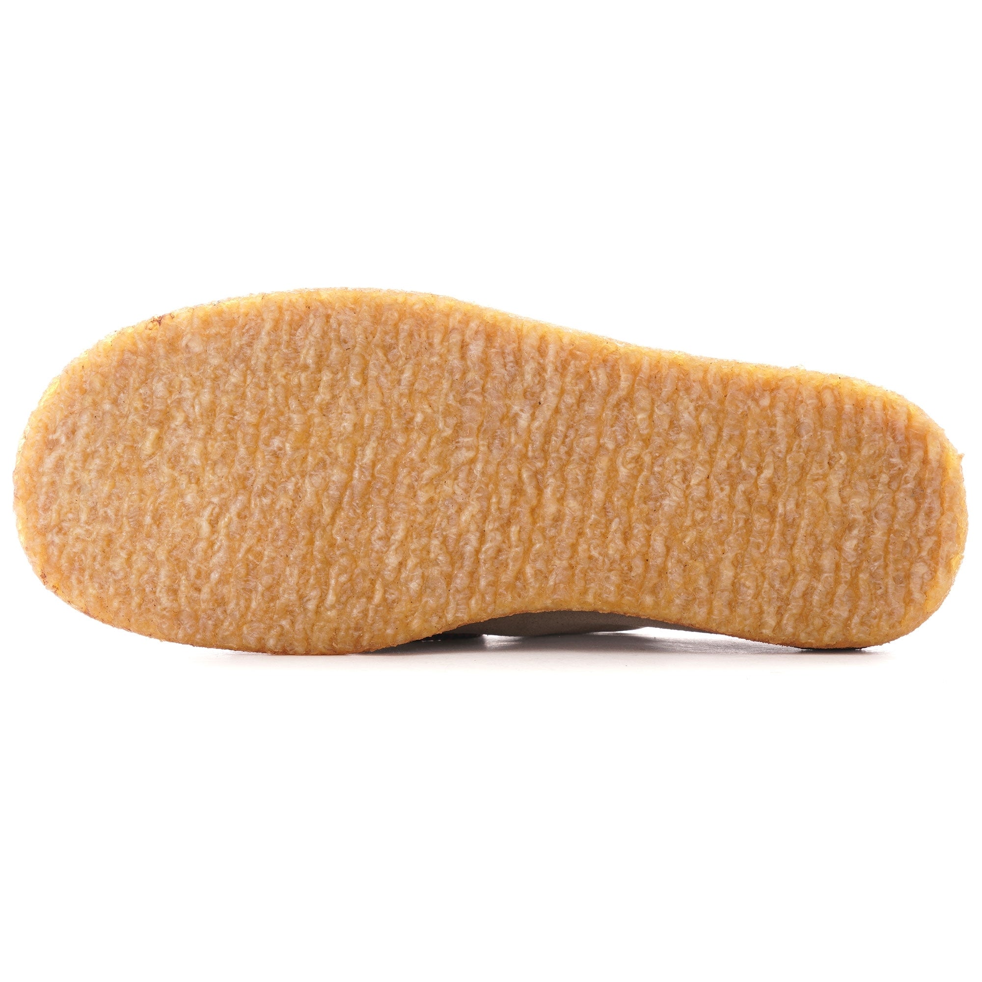 The textured rubber sole of a taupe suede shoe.