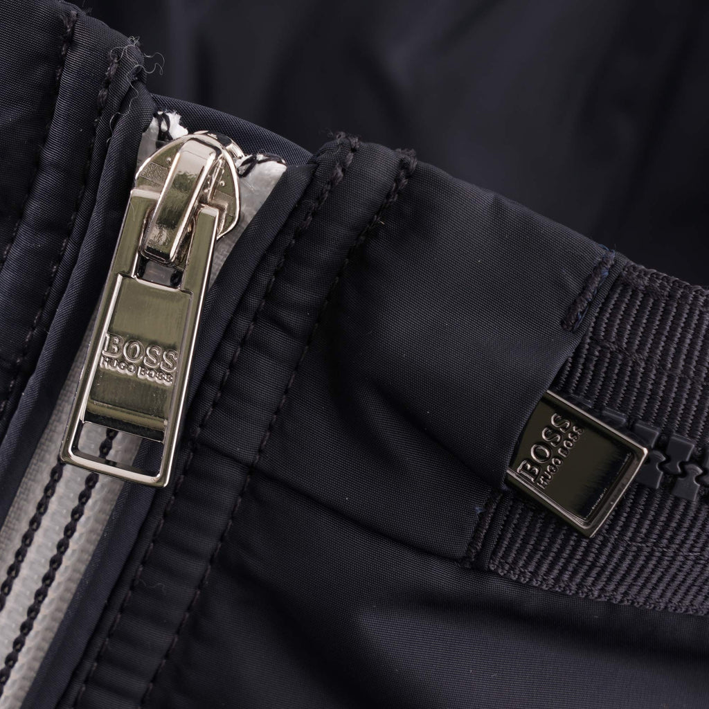 Detail of the jacket's main zip puller and a branded metallic tag.