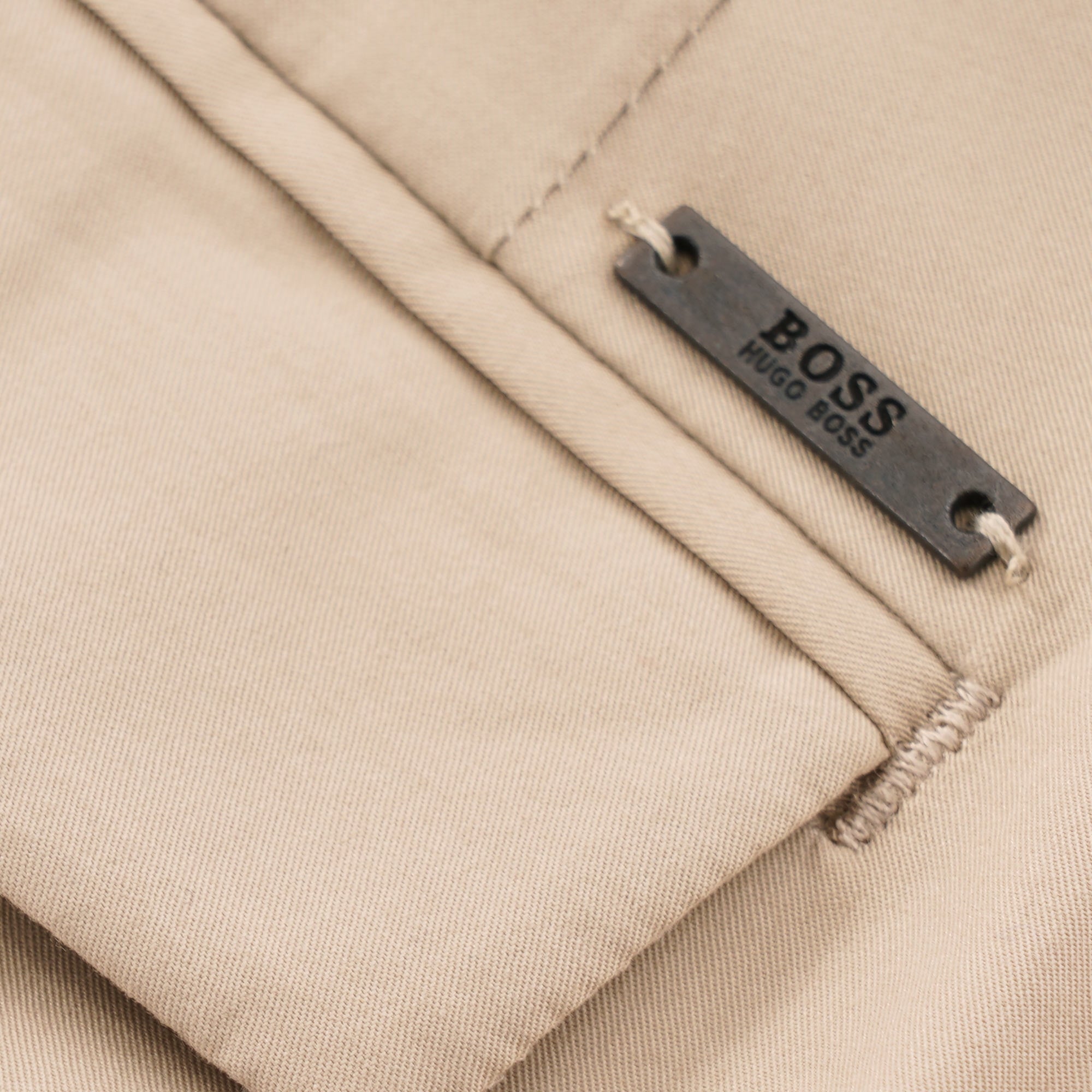 Close-up of a Hugo Boss brand tag on beige fabric.