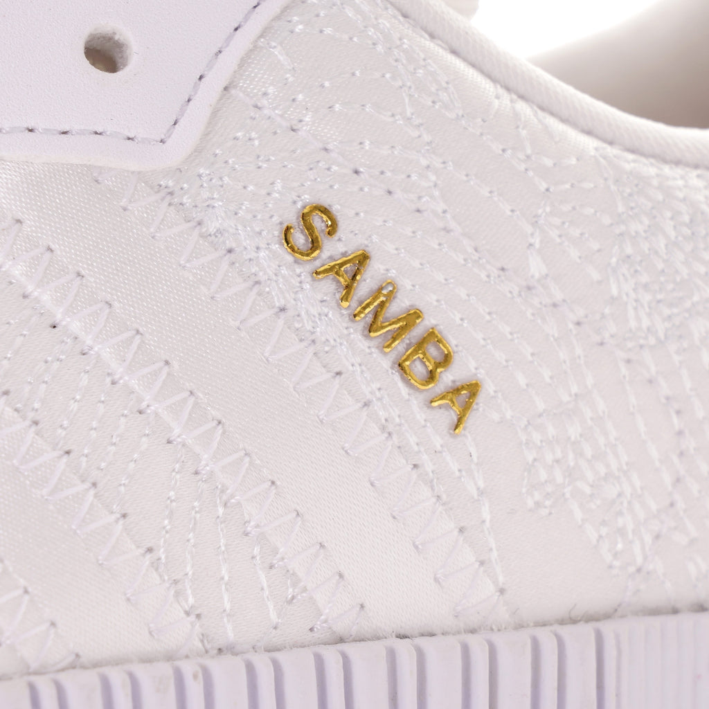 Close-up of the gold 'SAMBA' text on the side of a white Adidas Sambarose trainer.