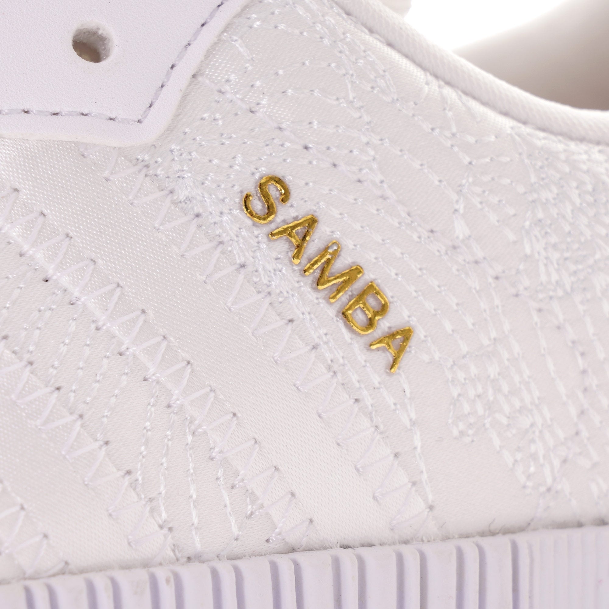 Close-up of the gold 'SAMBA' text on the side of a white Adidas Sambarose trainer.