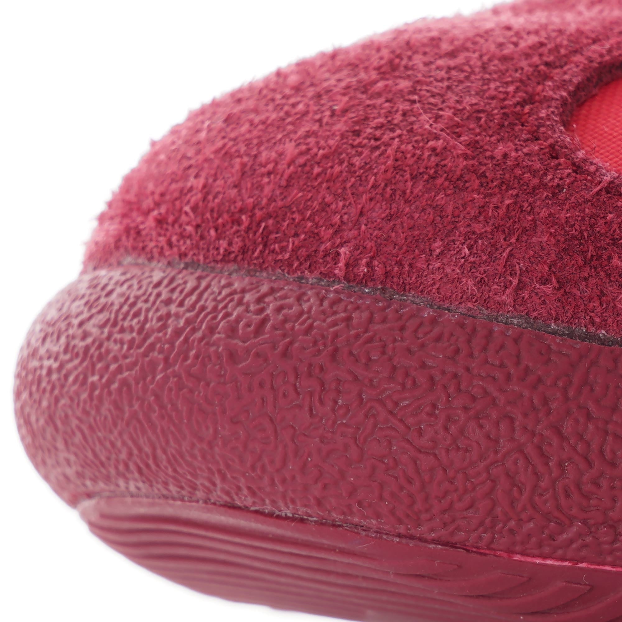 A close-up shot of the textured red rubber toe cap and suede upper of the trainer.