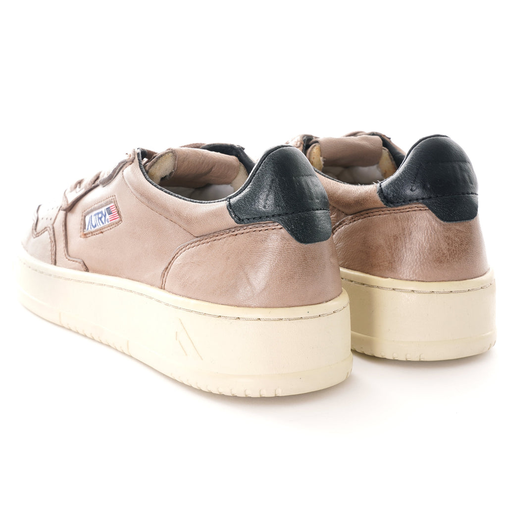Rear view of a pair of Autry Medalist Low grey-brown leather sneakers with black heel tabs.