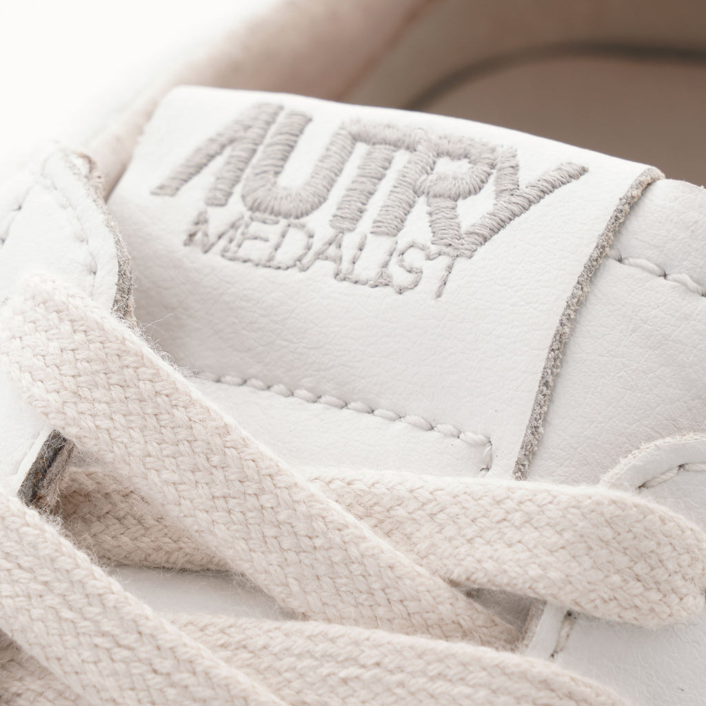 Close-up of the "AUTRY MEDALIST" logo on the tongue of a white trainer.