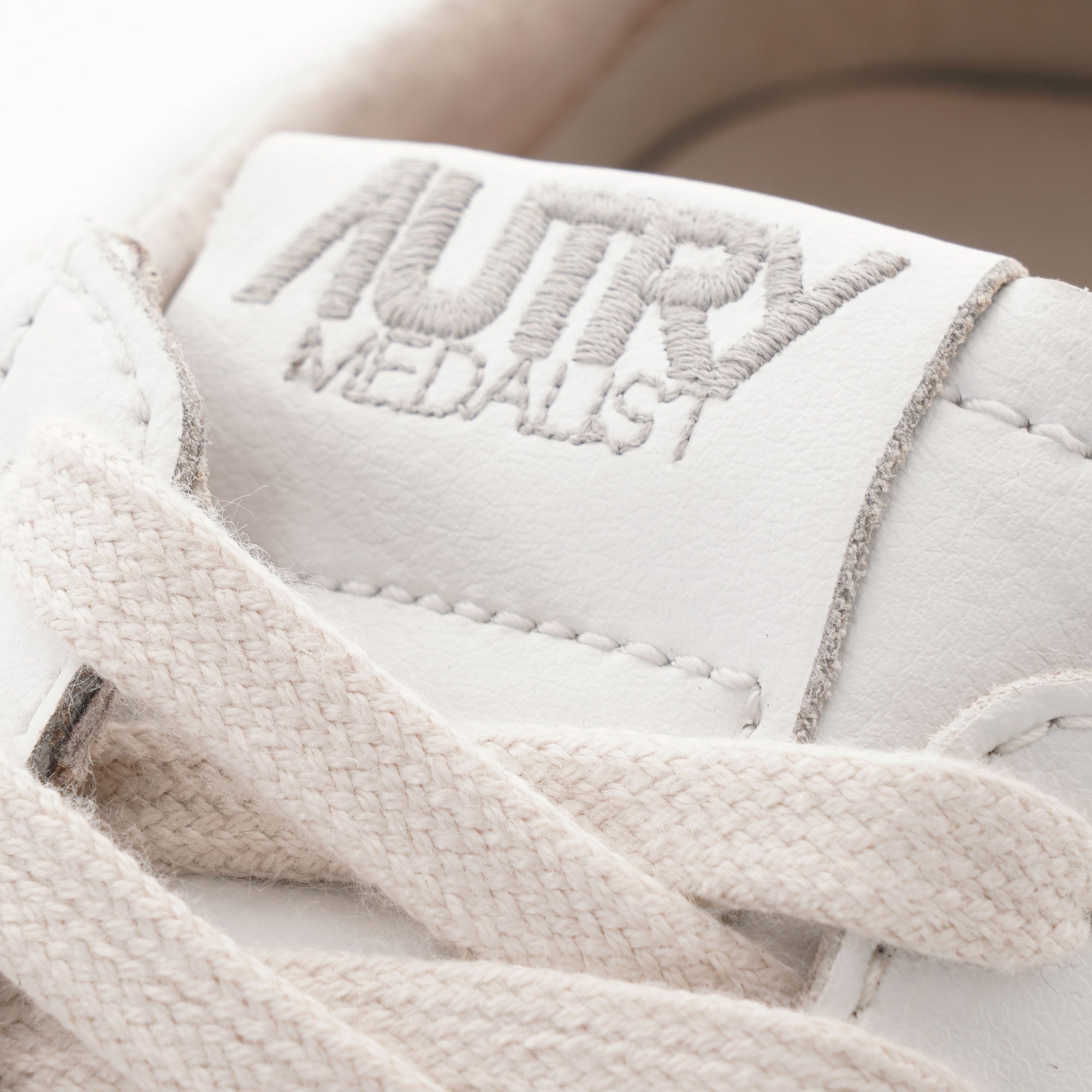 Close-up of the "AUTRY MEDALIST" logo on the tongue of a white trainer.
