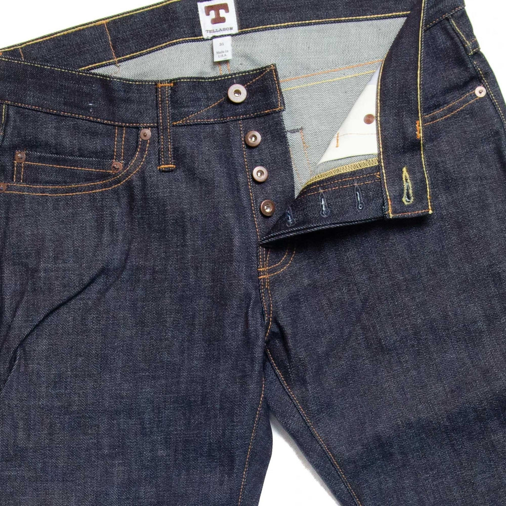Close-up of the jeans' fly, highlighting the button closure and contrast stitching.