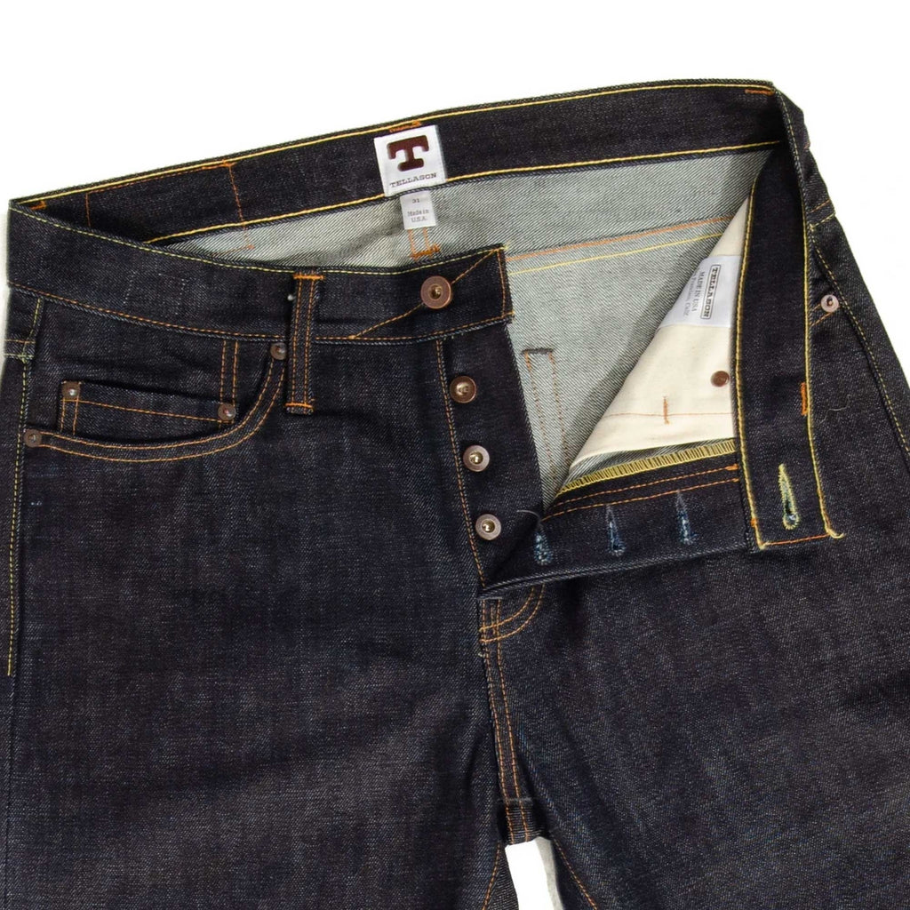 Close-up of the waist and fly of dark wash selvedge denim jeans, unbuttoned.