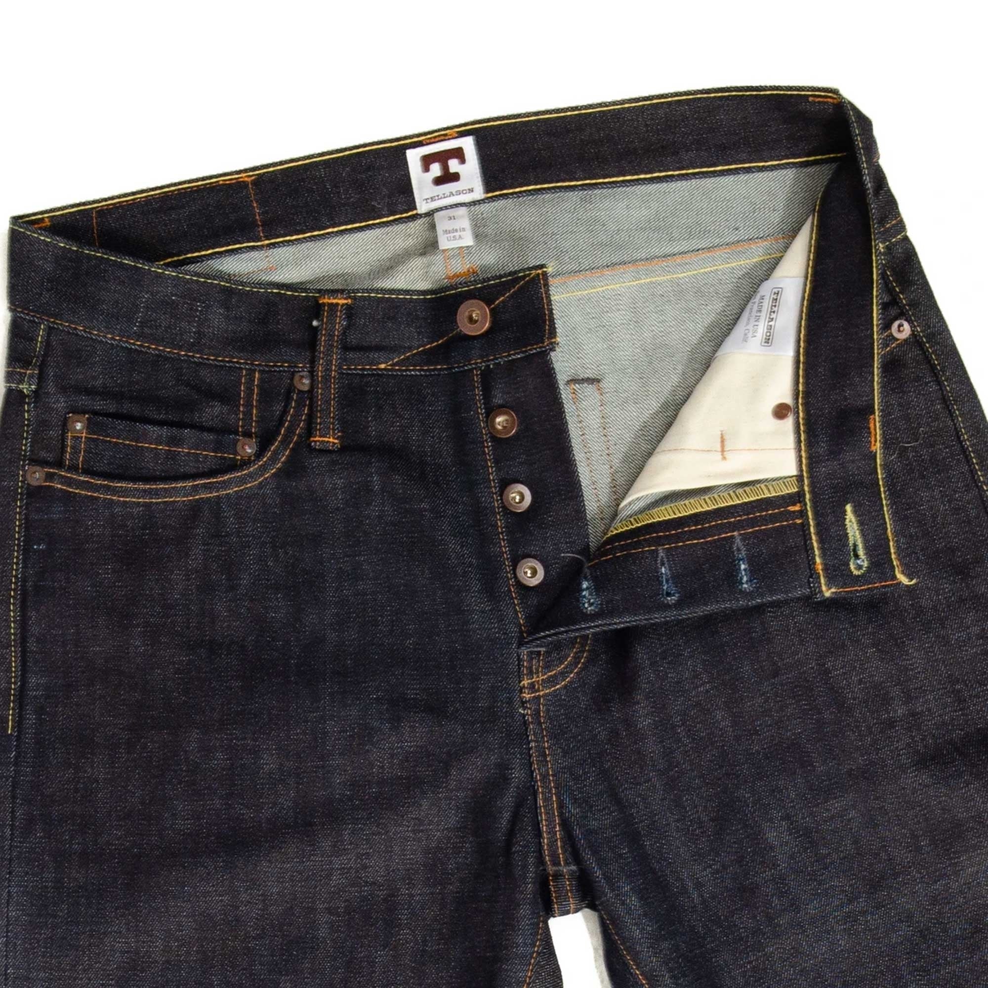 Close-up of the waist and fly of dark wash selvedge denim jeans, unbuttoned.