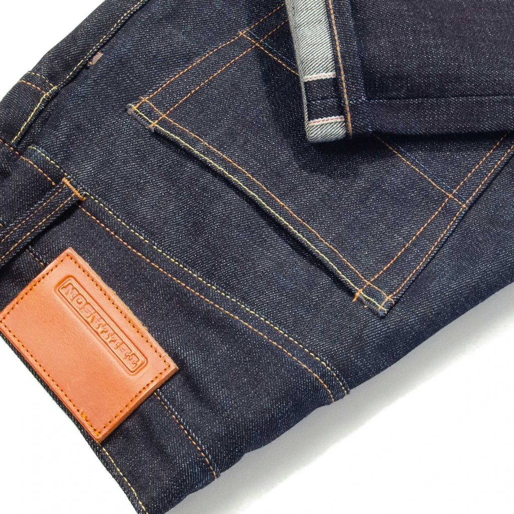 Close-up of dark blue denim jeans showing the rear pocket, leather patch, and cuff.