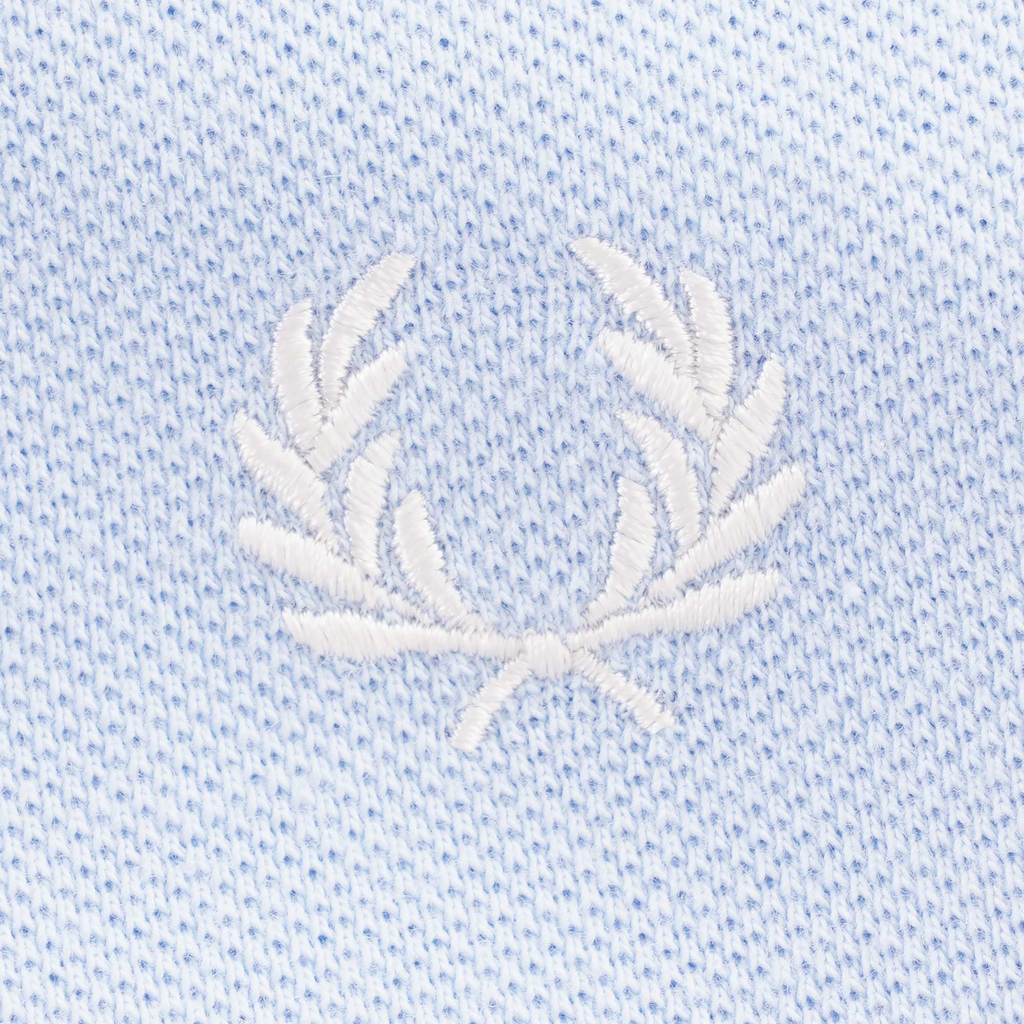 Close-up of the white embroidered Fred Perry laurel wreath logo on light blue fabric.