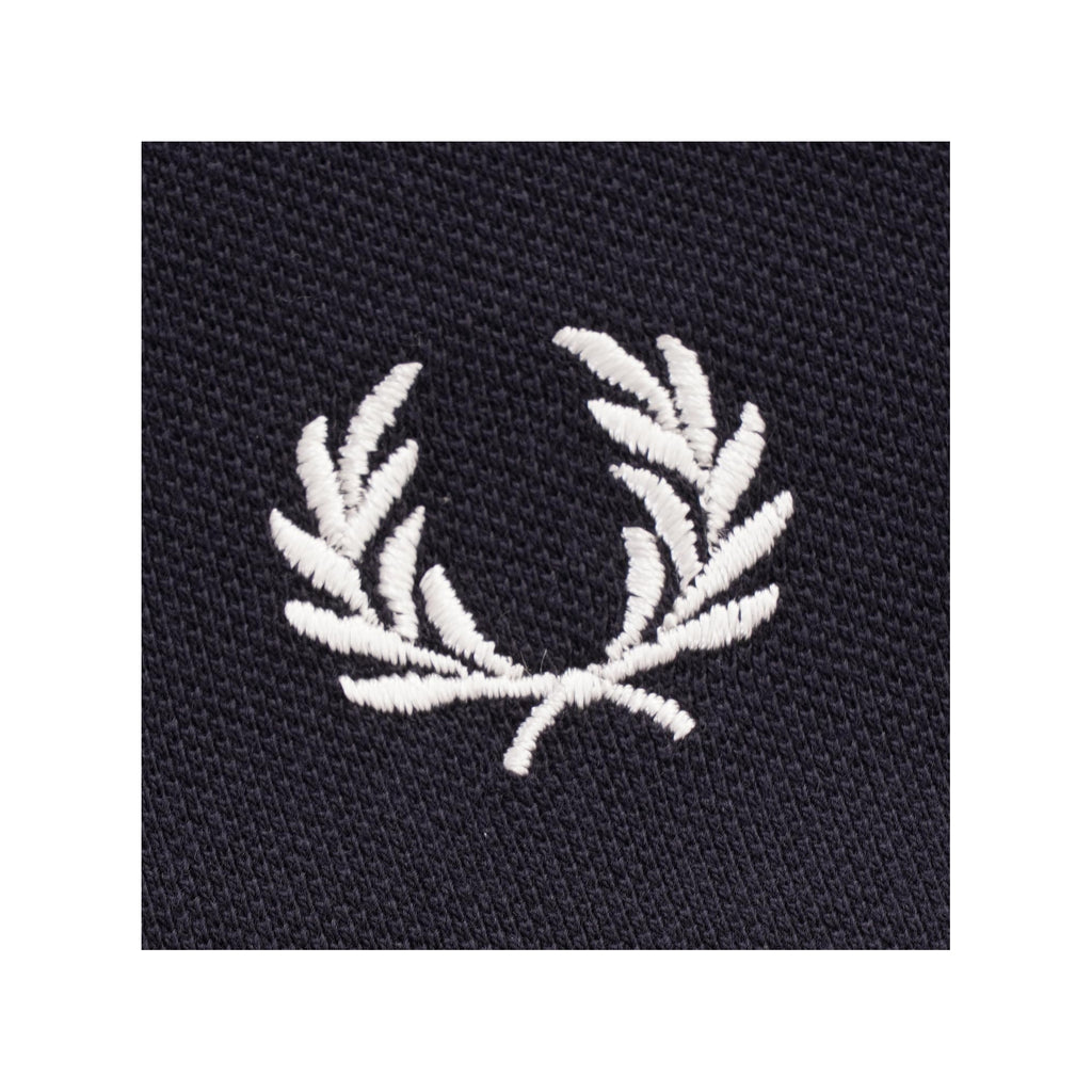A close-up of the embroidered white Fred Perry laurel wreath logo on the shirt.