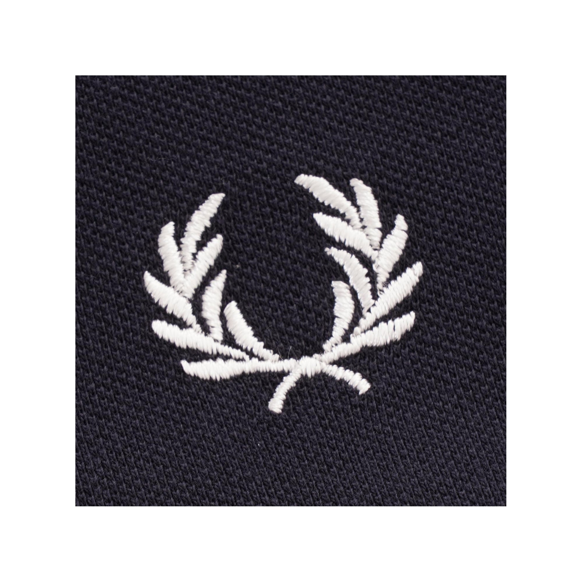 A close-up of the embroidered white Fred Perry laurel wreath logo on the shirt.