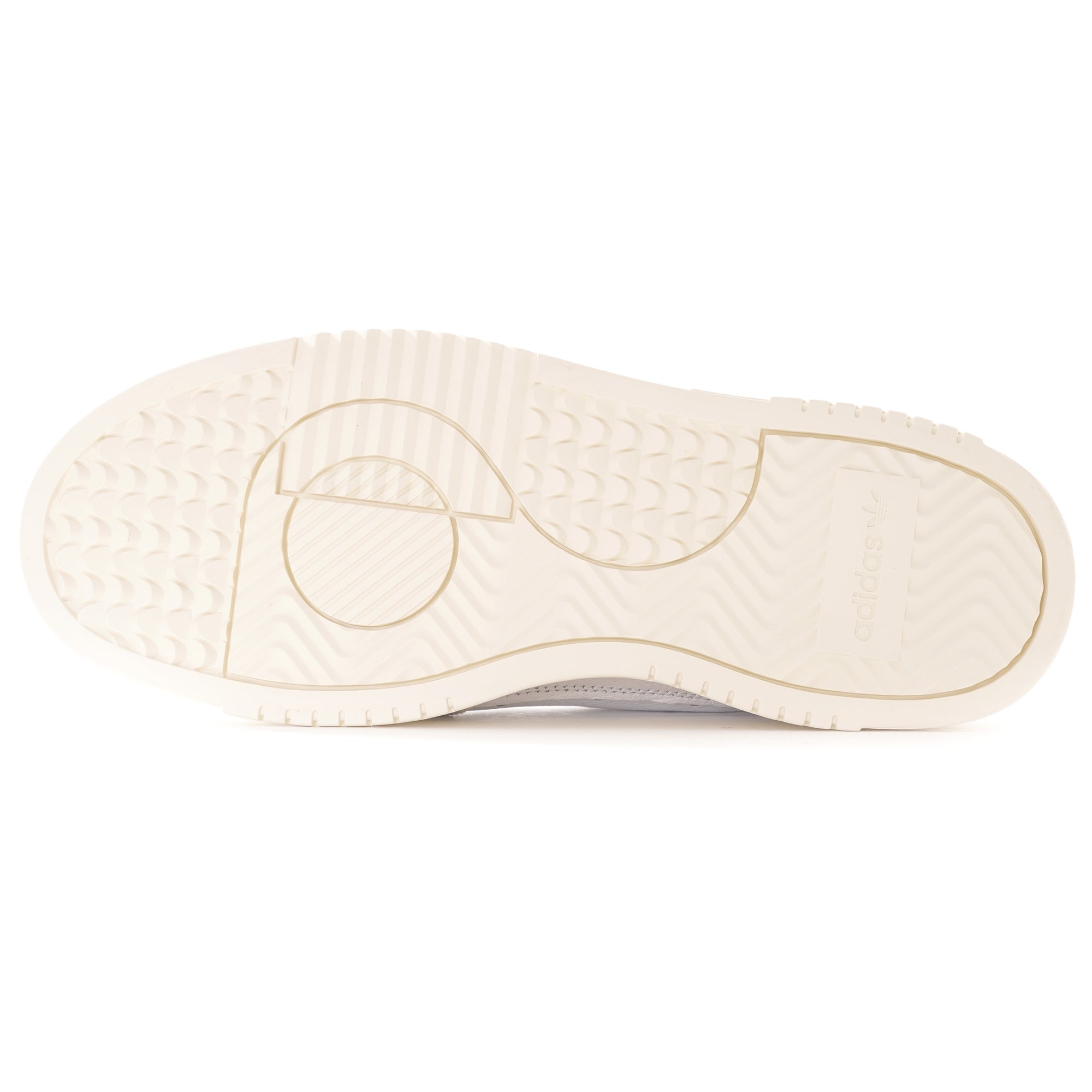 The textured cream sole of a white adidas Supercourt sneaker.