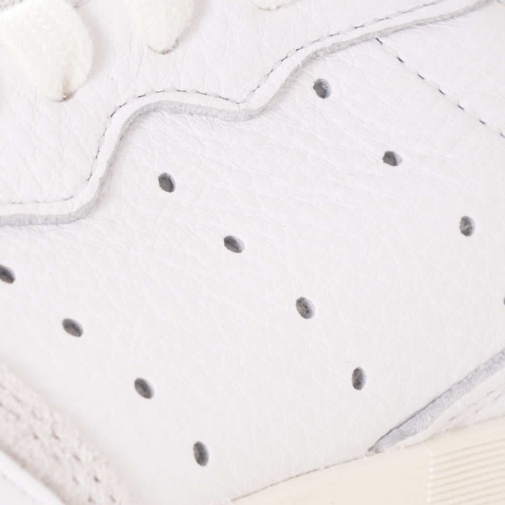 A close-up of the perforated detail on the side of a white adidas Supercourt sneaker.