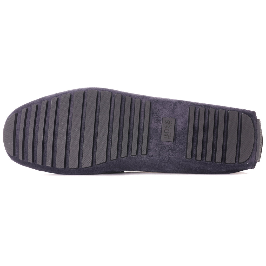 The textured rubber sole of a dark blue suede loafer, with vertical grips.