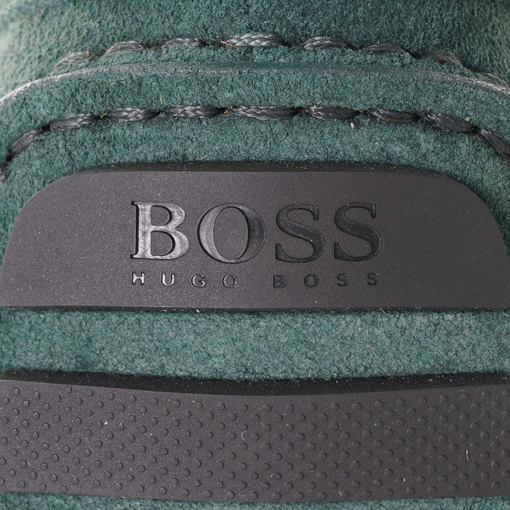 Close-up of the BOSS logo embossed on the heel of a green suede loafer.