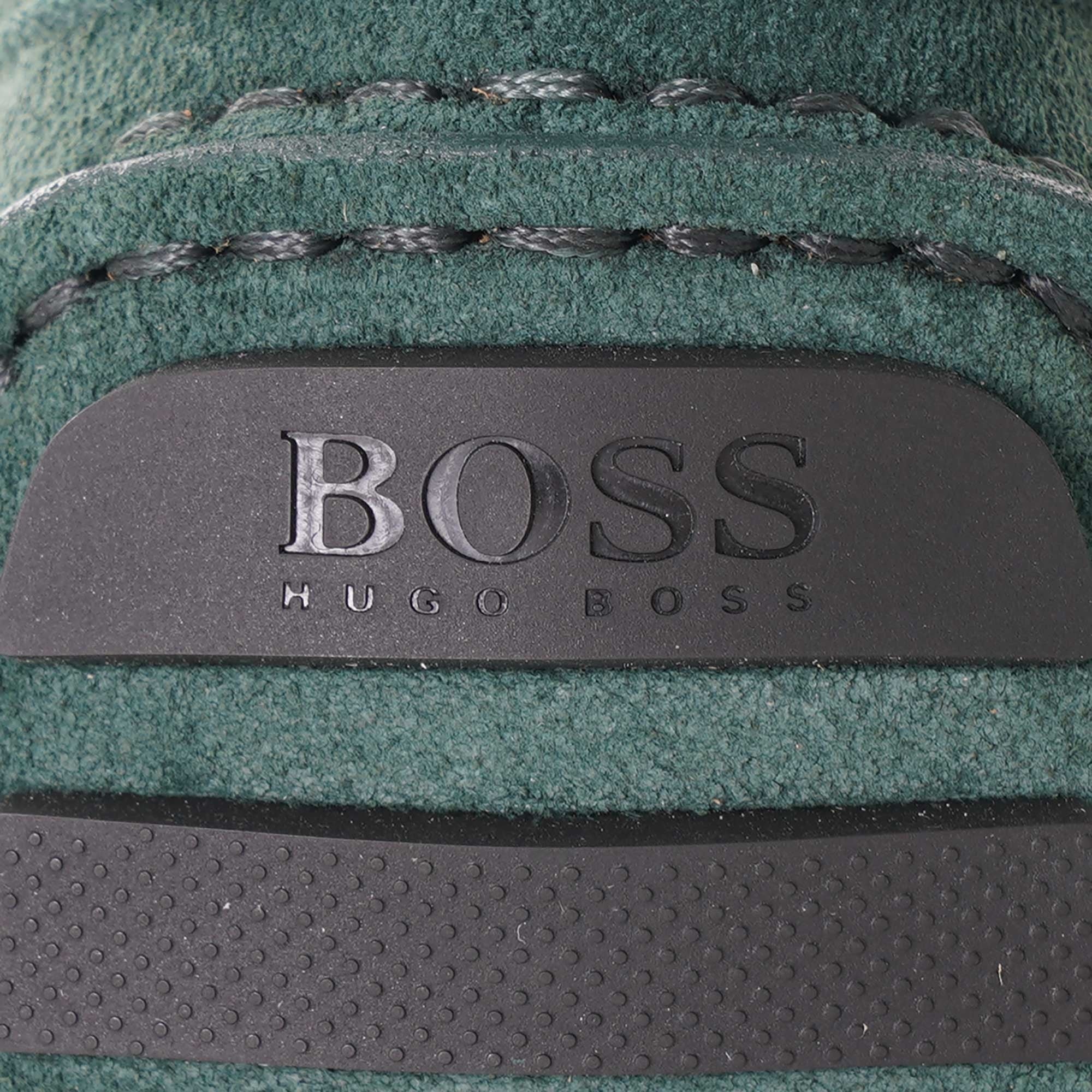 Close-up of the BOSS logo embossed on the heel of a green suede loafer.