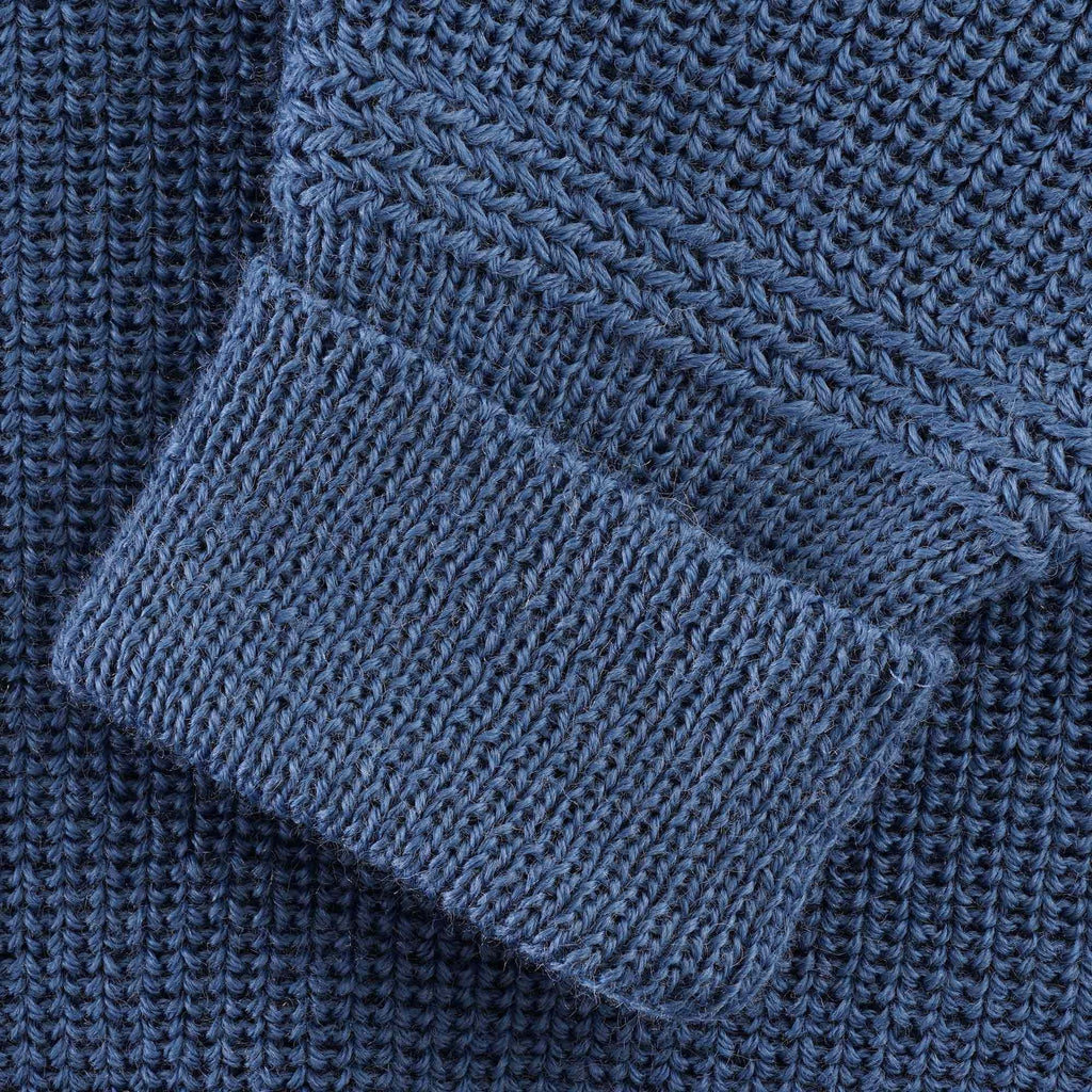 Close-up of the ribbed cuff and knit detail on the blue jumper sleeve.