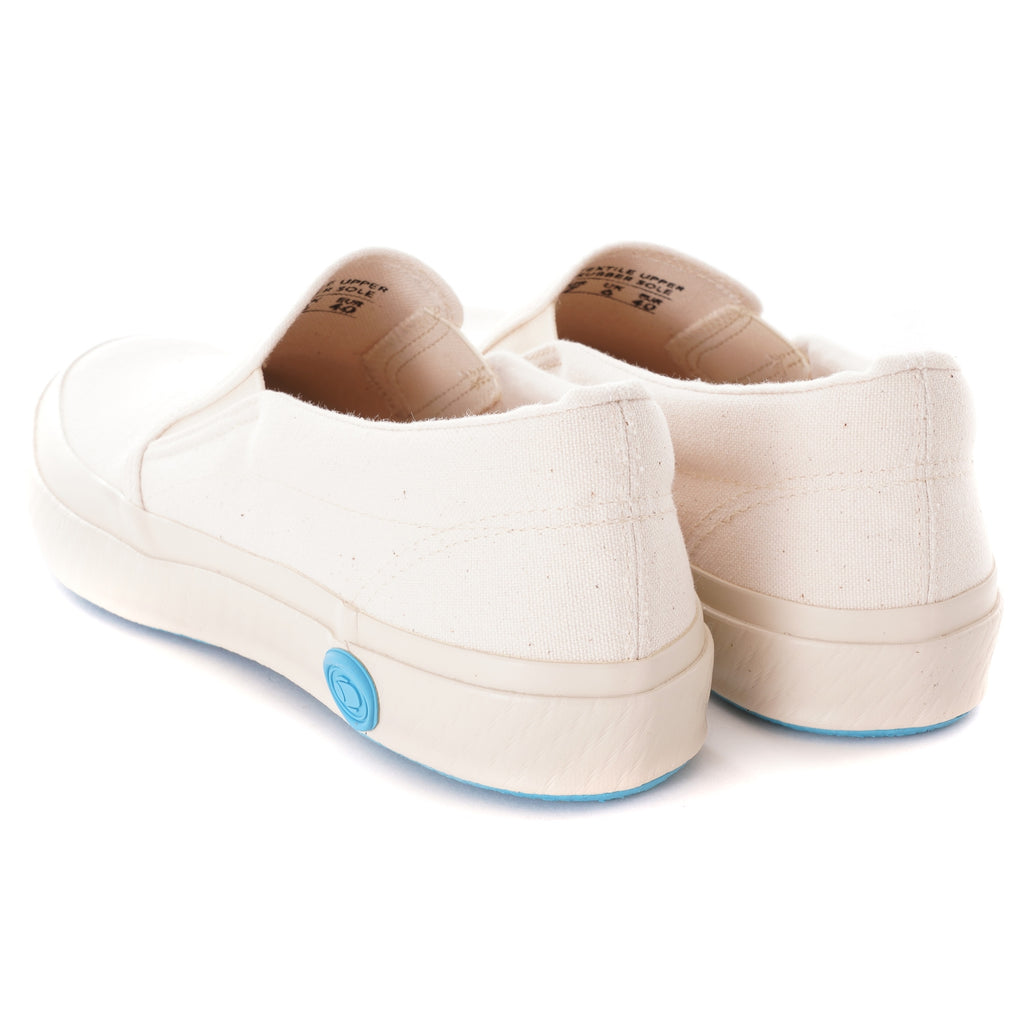 A pair of white slip-on canvas shoes with light blue soles are shown from the back.