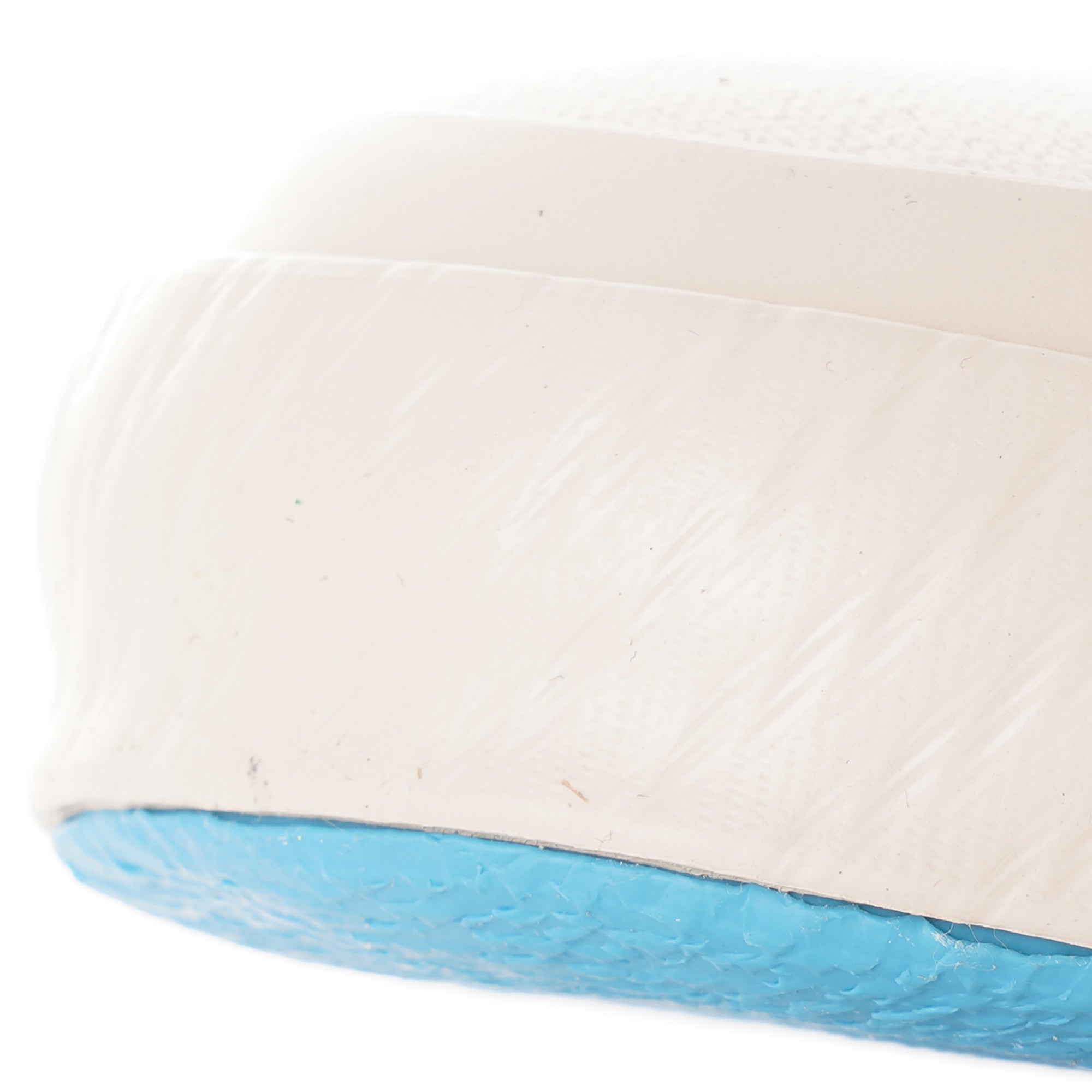 A close-up of the textured white rubber trim and light blue sole of a shoe.
