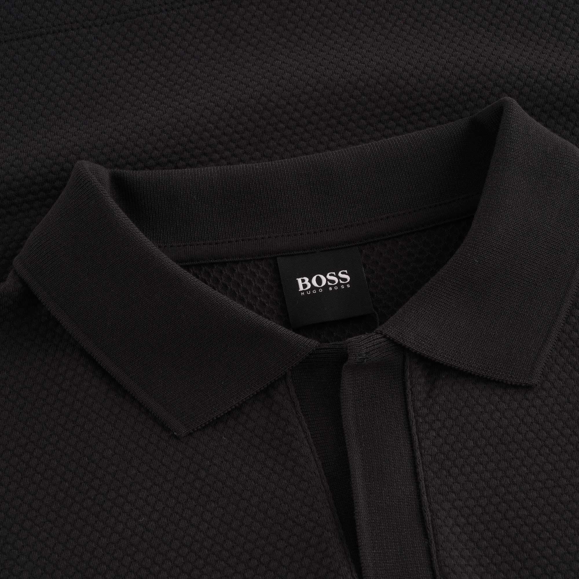 Close-up of the BOSS brand label on a black polo shirt collar.