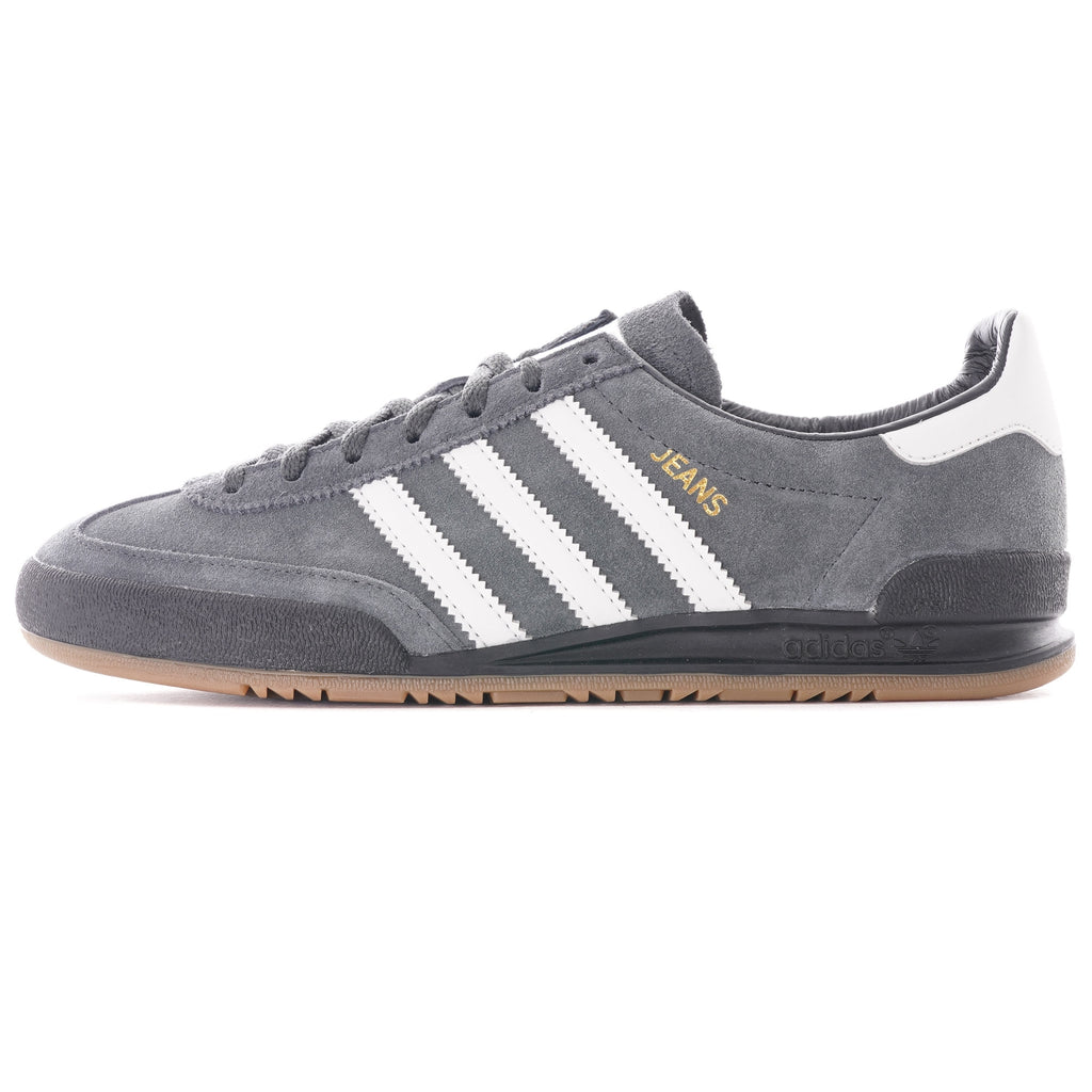 A grey Adidas Jeans trainer with white stripes and a brown sole, viewed from the side.