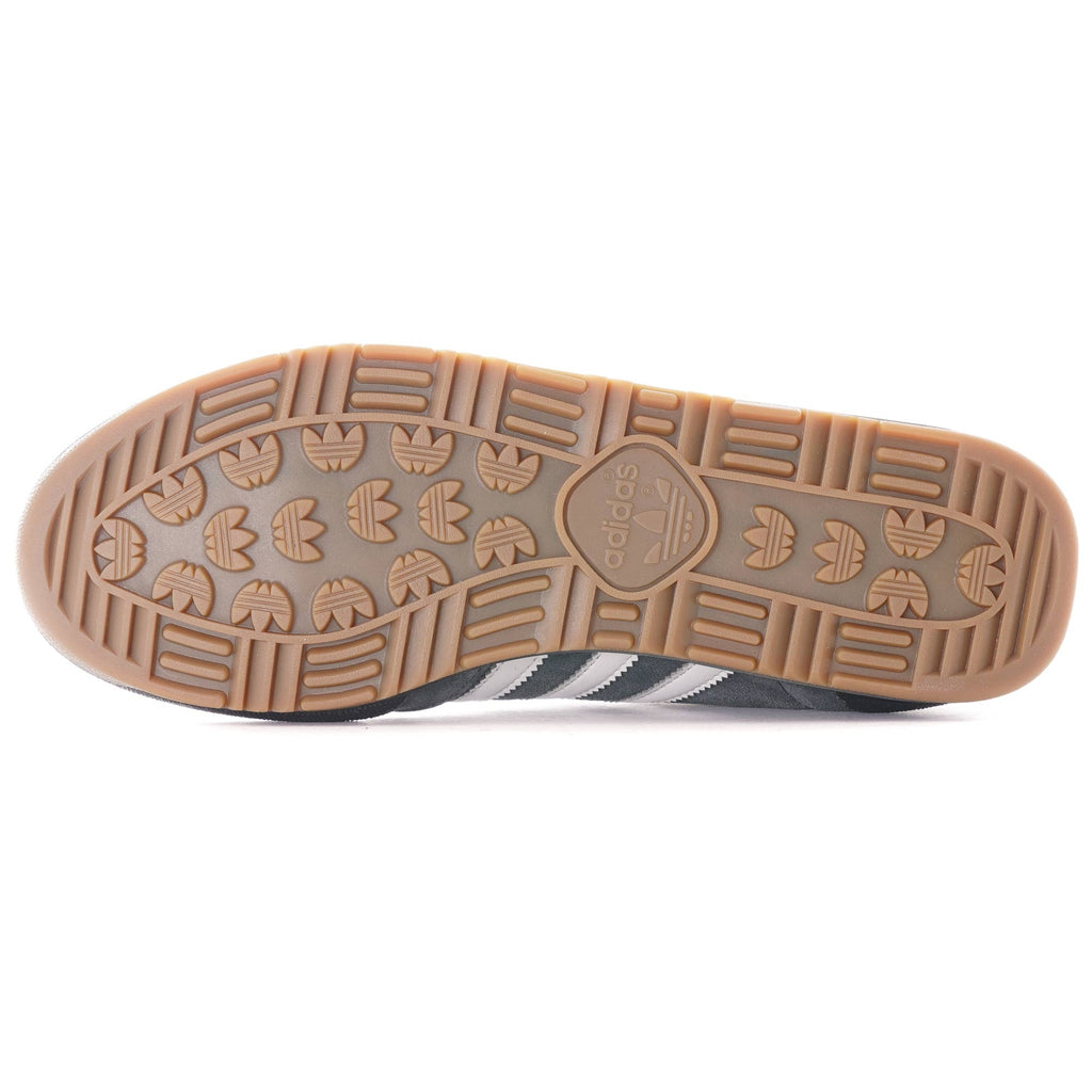 The textured brown sole of a grey Adidas Jeans trainer.