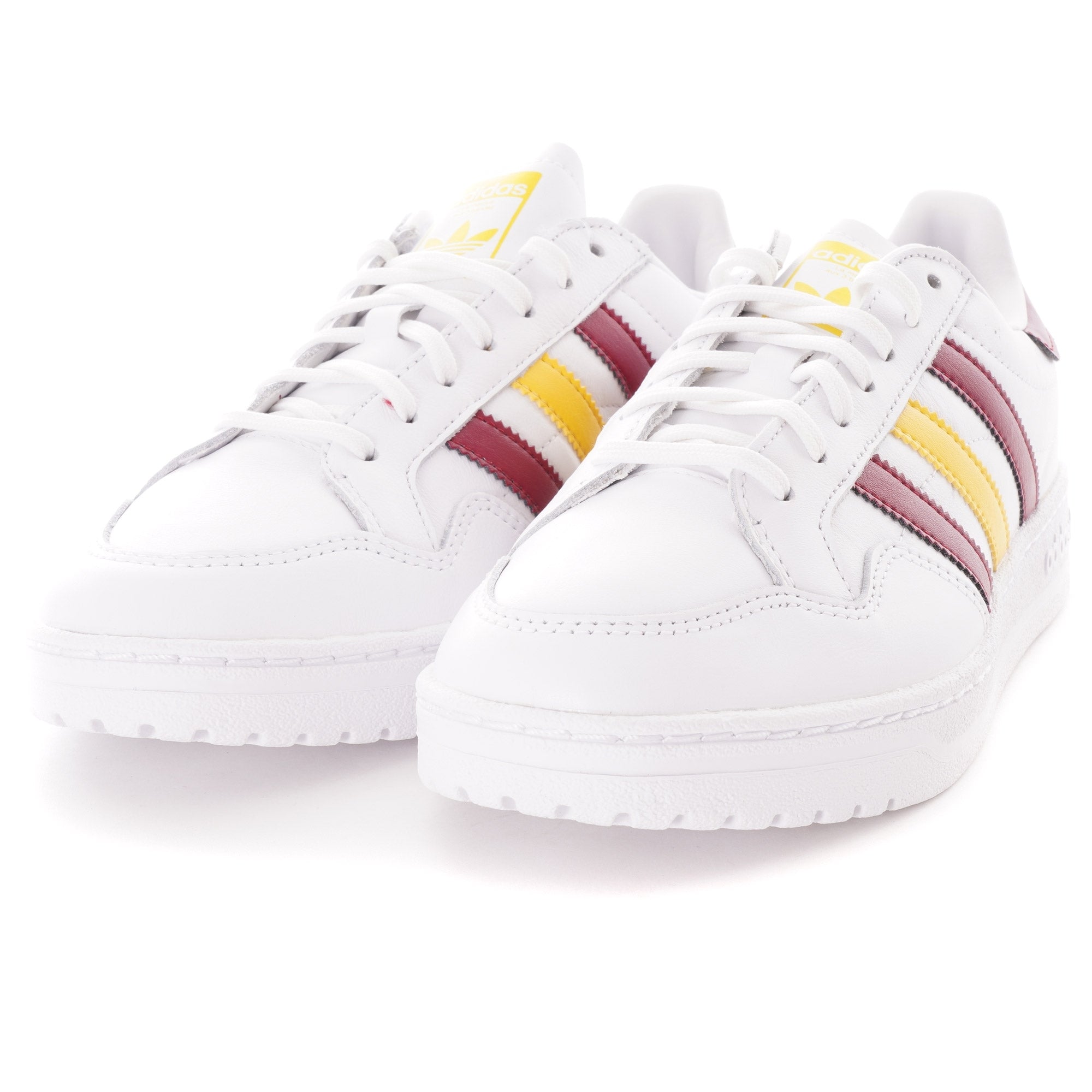 Pair of white Adidas trainers with burgundy and yellow stripes, angled slightly.