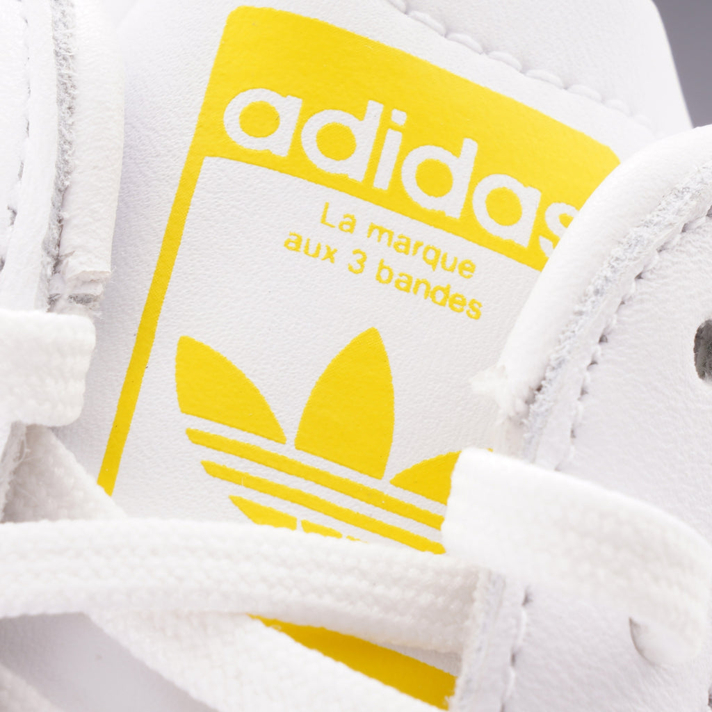 Close-up of the yellow Adidas logo label on the tongue of a trainer.