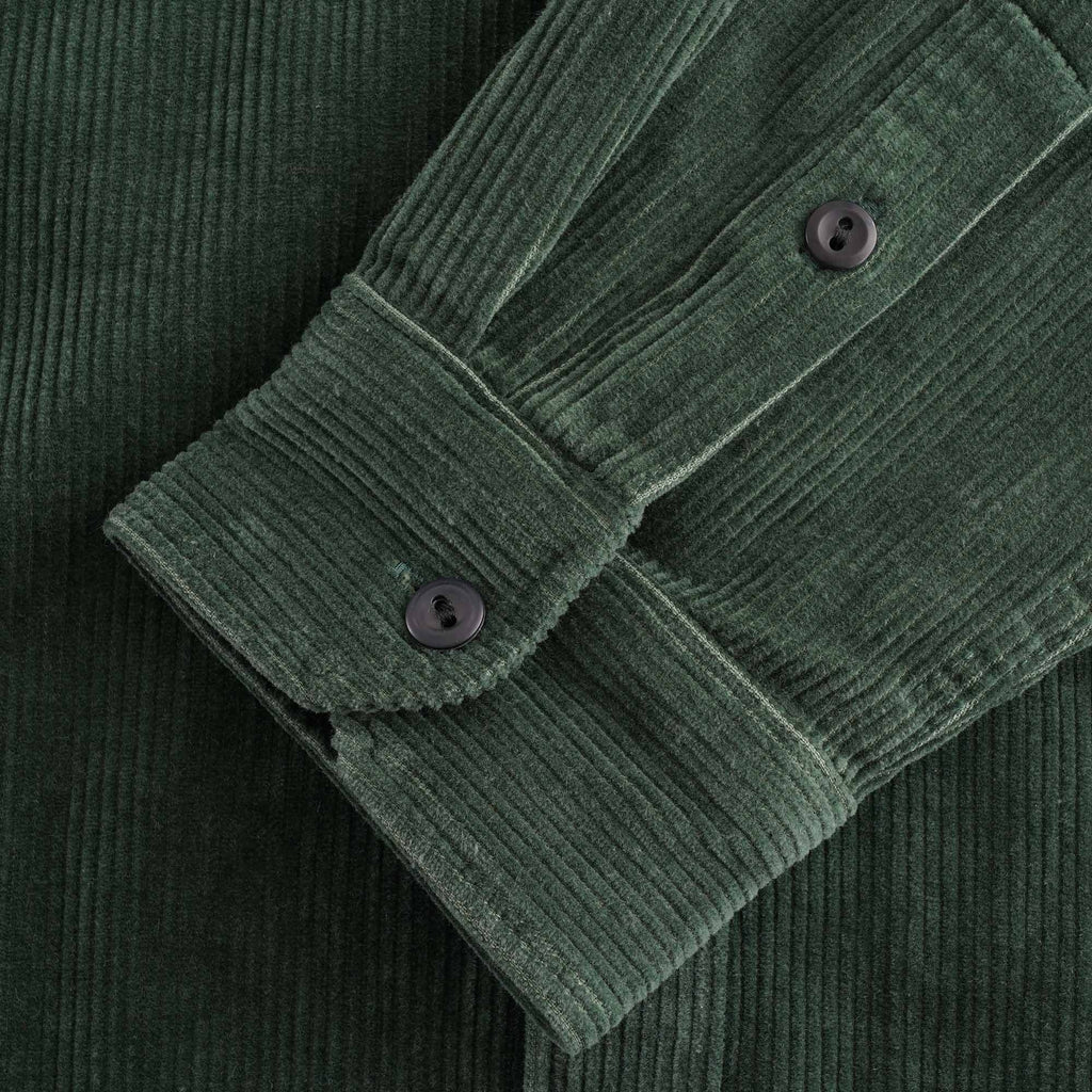 Detailed view of the cuff and buttons on a green corduroy shirt.