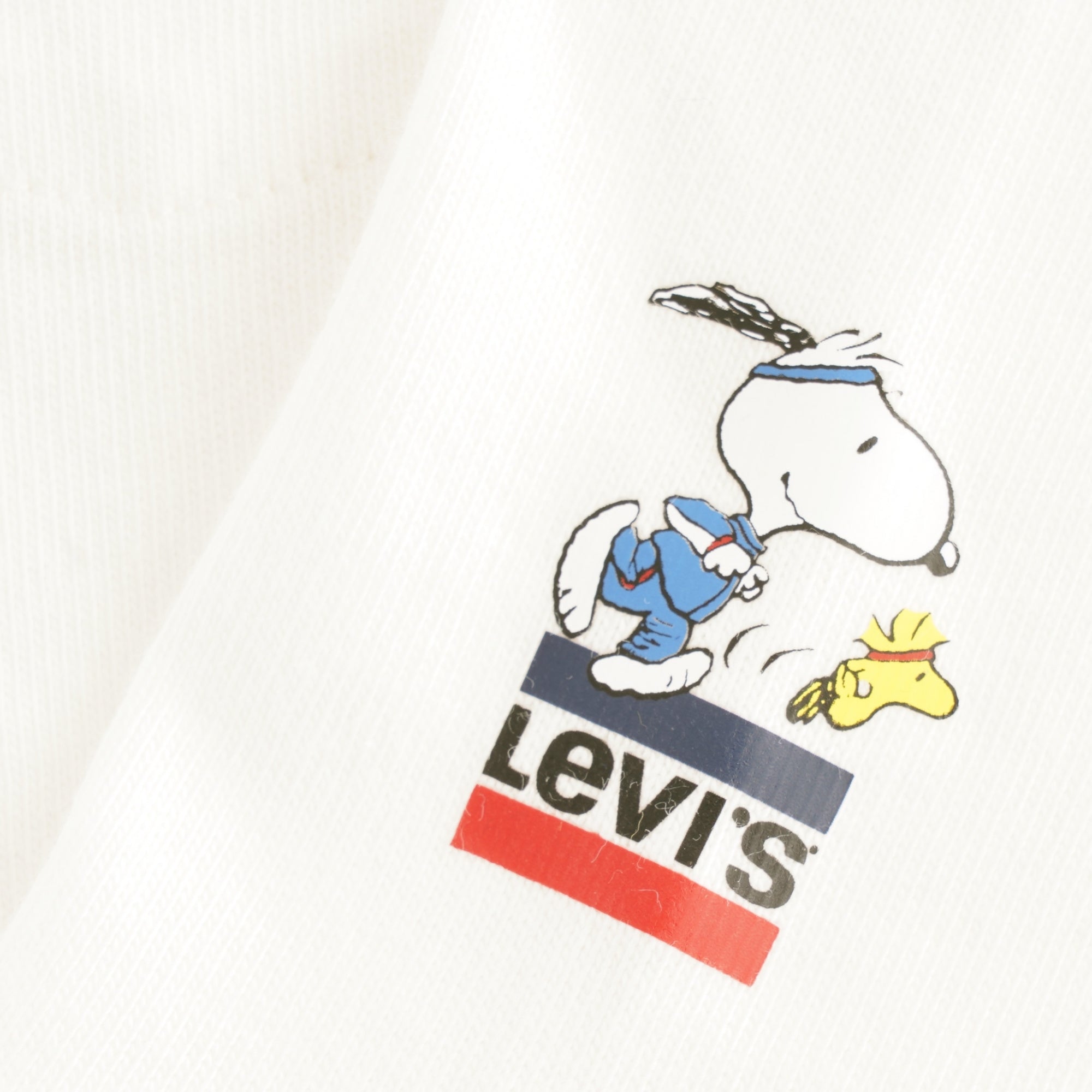 A close-up of the Levi's logo and Snoopy playing tennis on a white t-shirt.