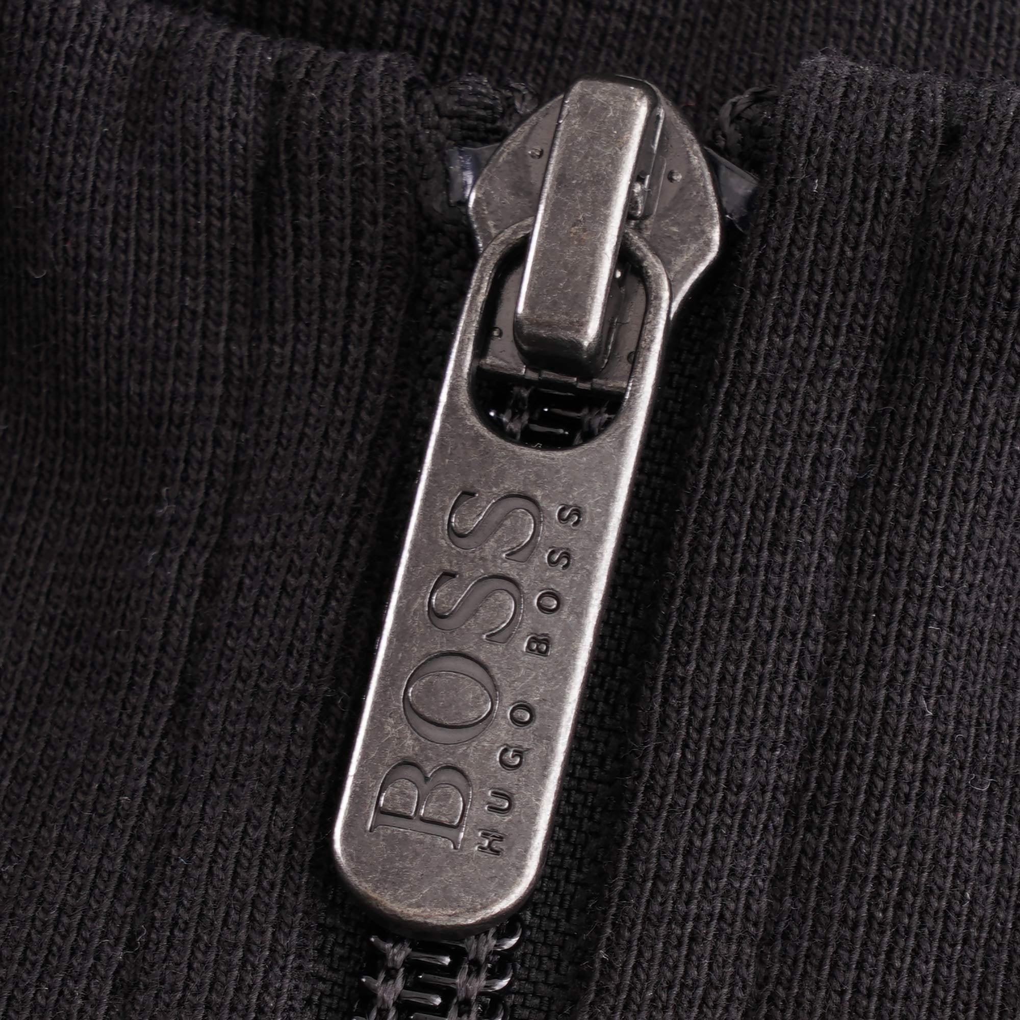 A close-up of the silver BOSS Hugo Boss branded zip pull on the black track jacket.