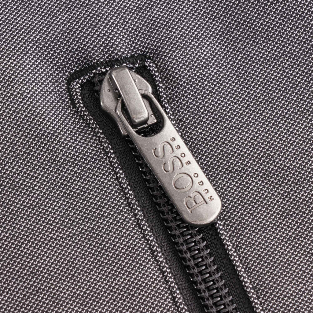 Close-up of the silver BOSS branded zip pull on the grey pocket of the track jacket.