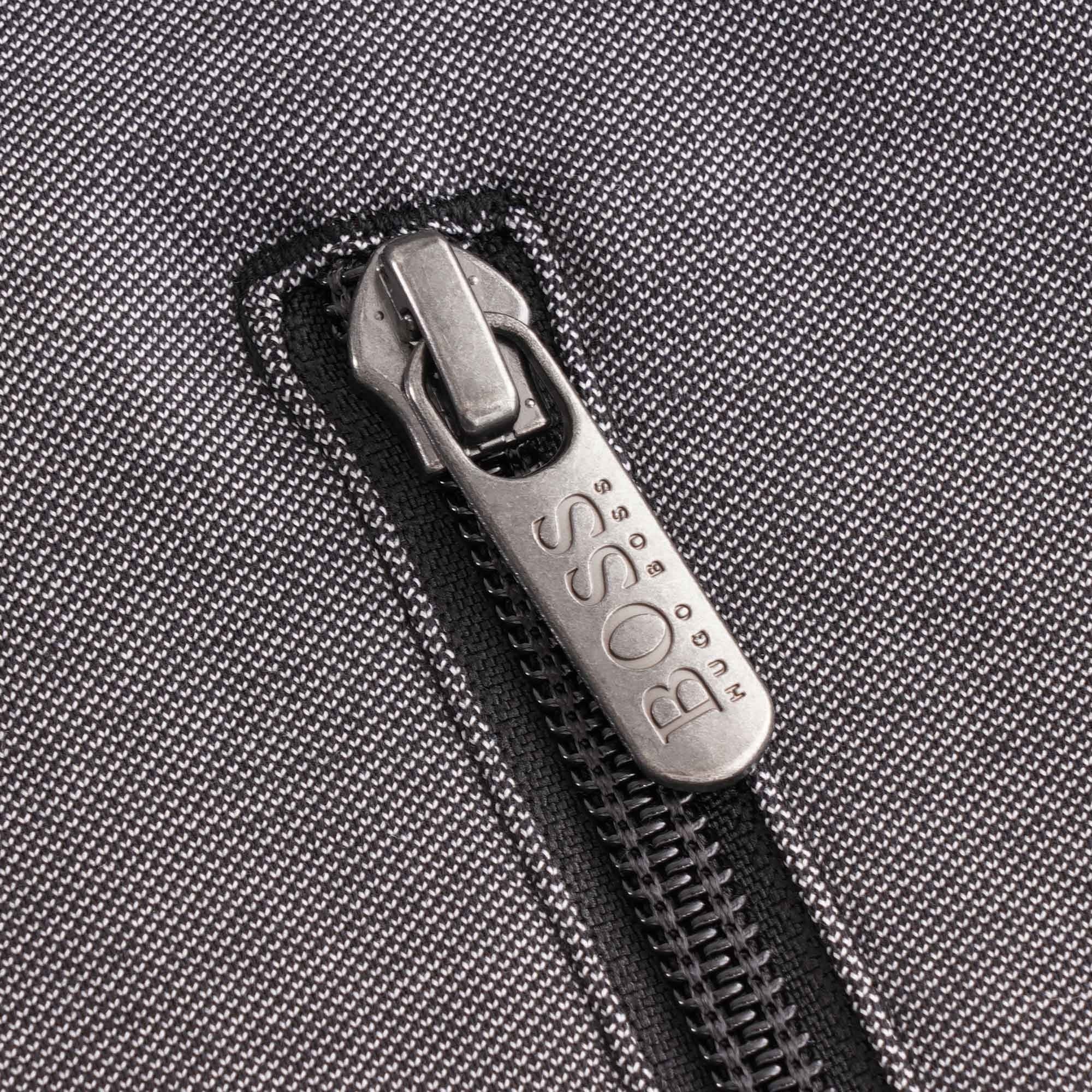 Close-up of the silver BOSS branded zip pull on the grey pocket of the track jacket.