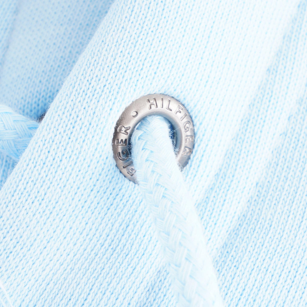 Detail of the eyelet on the hoodie's drawstring, featuring the Hilfiger logo.