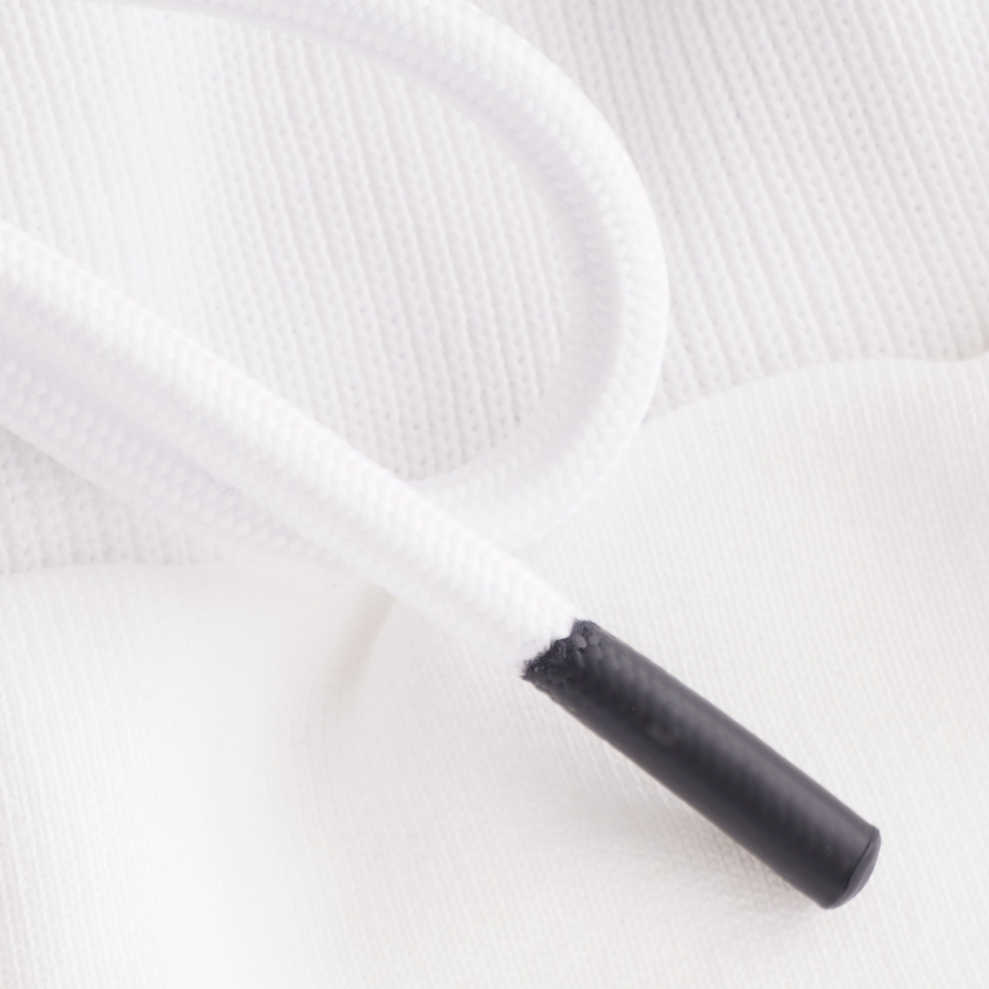 Close-up of a white drawstring with black aglet on swim shorts.