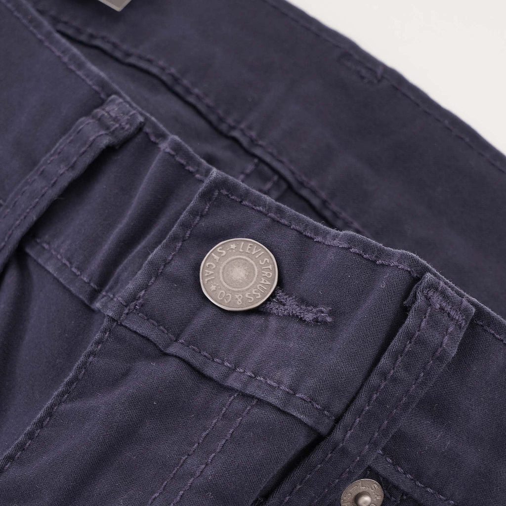 Close-up of the button fastening on navy Levi's 511 corduroy trousers.