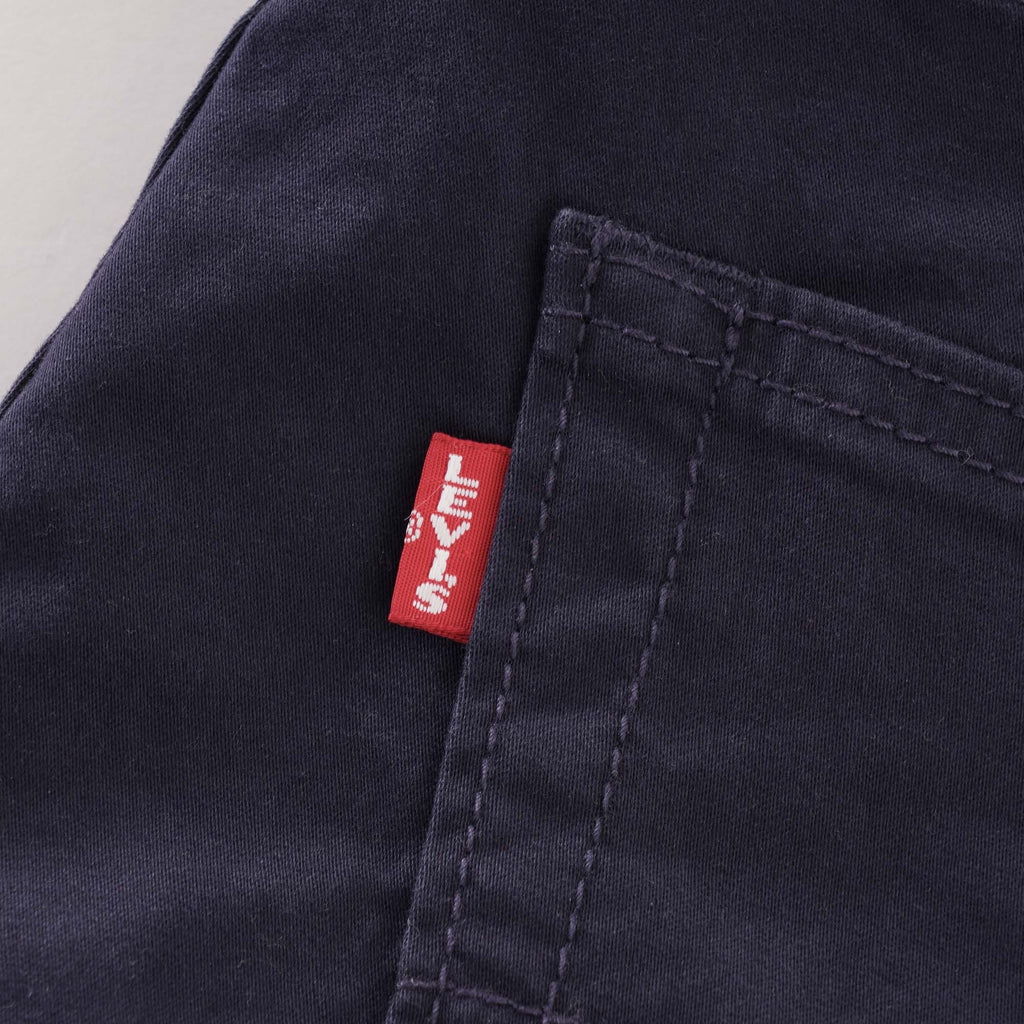 Close-up of the red Levi's tab on the rear pocket of navy corduroy trousers.