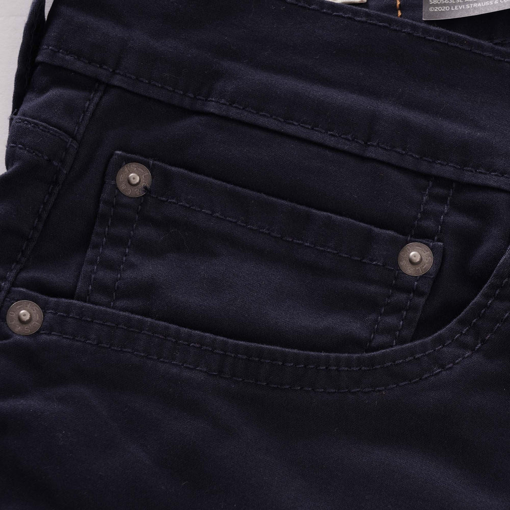 Close-up of the front coin pocket and rivets on navy corduroy trousers.