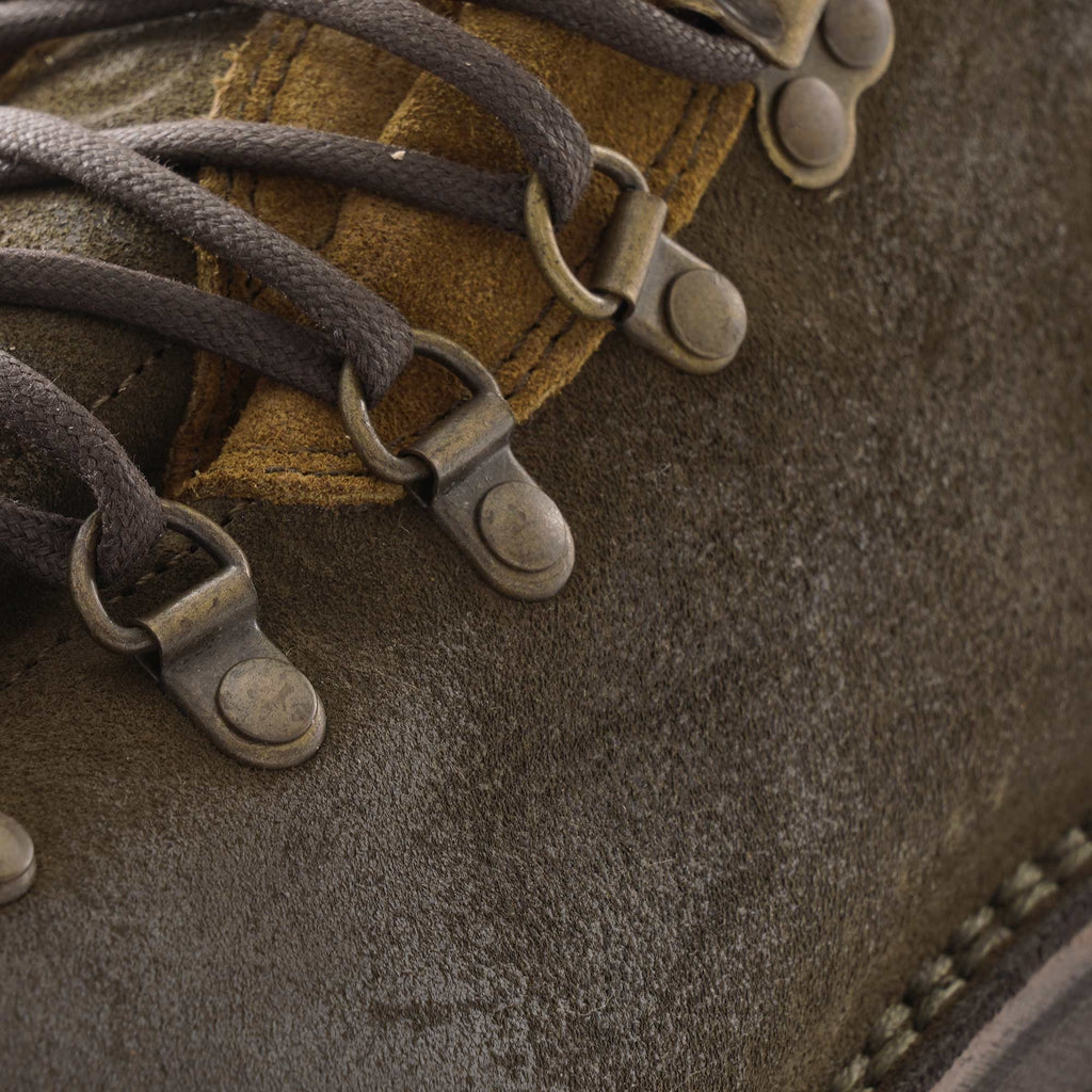 A close-up of the lacing eyelets and dark laces on a dark olive-green hiking boot.