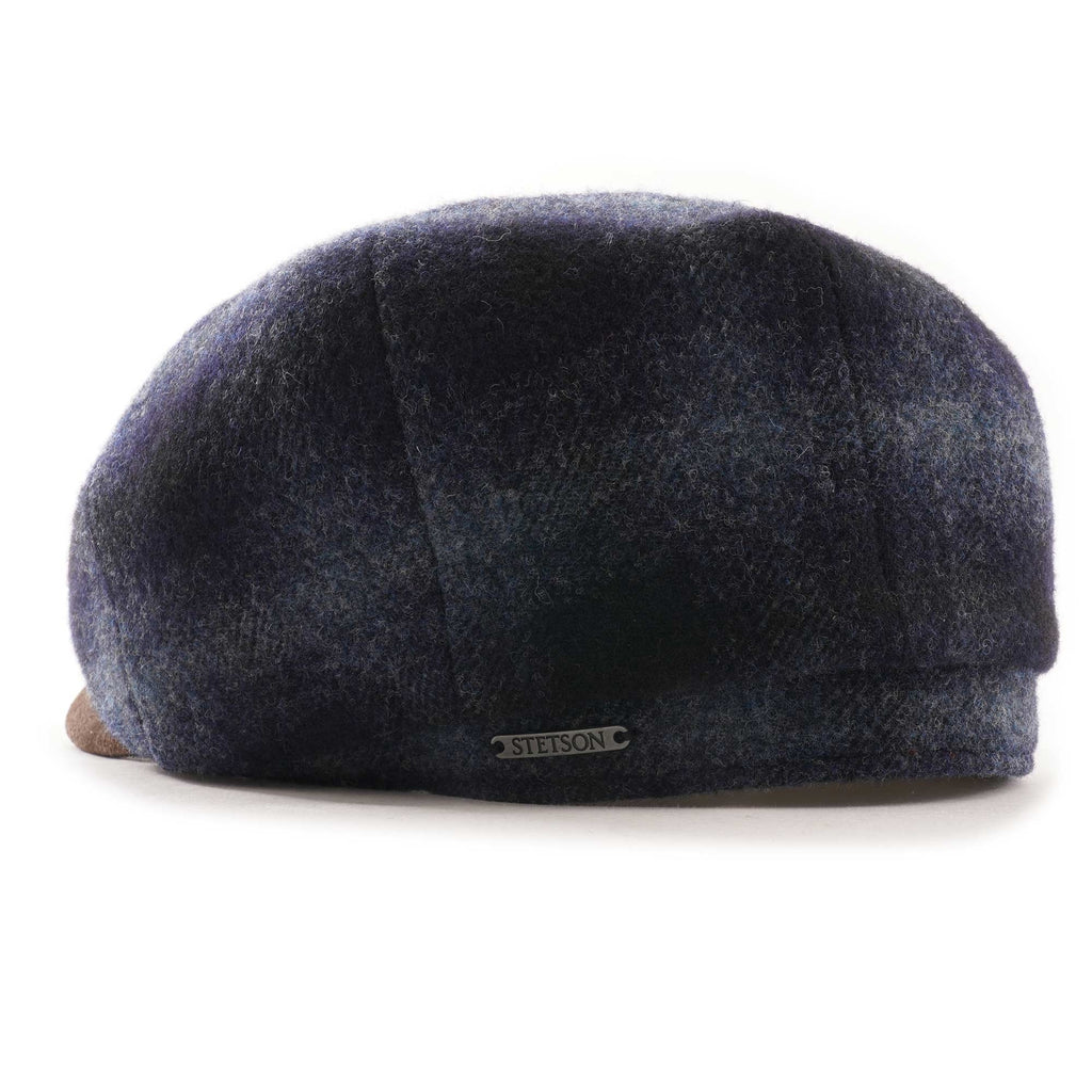 Rear view of a blue and black check flat cap with a brown suede peak.
