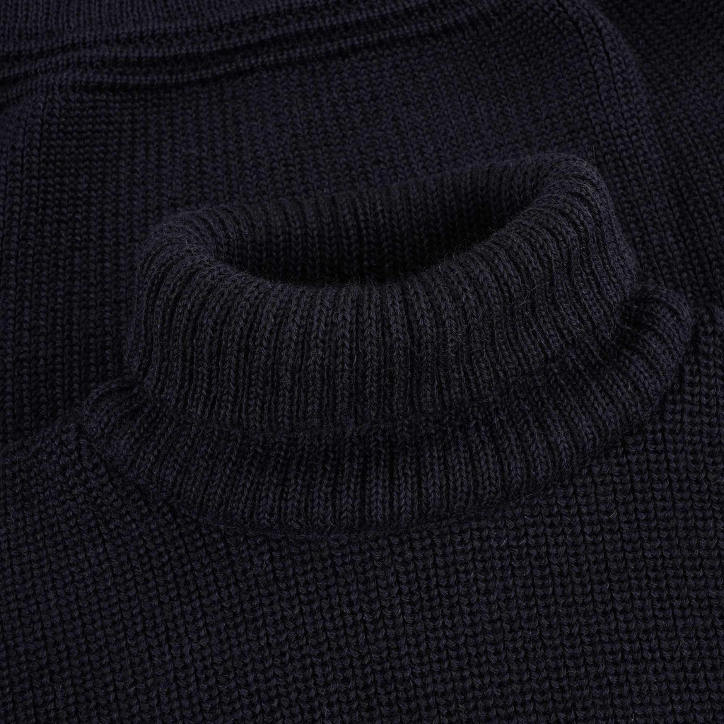 Close-up of the ribbed roll neck of a navy blue jumper.