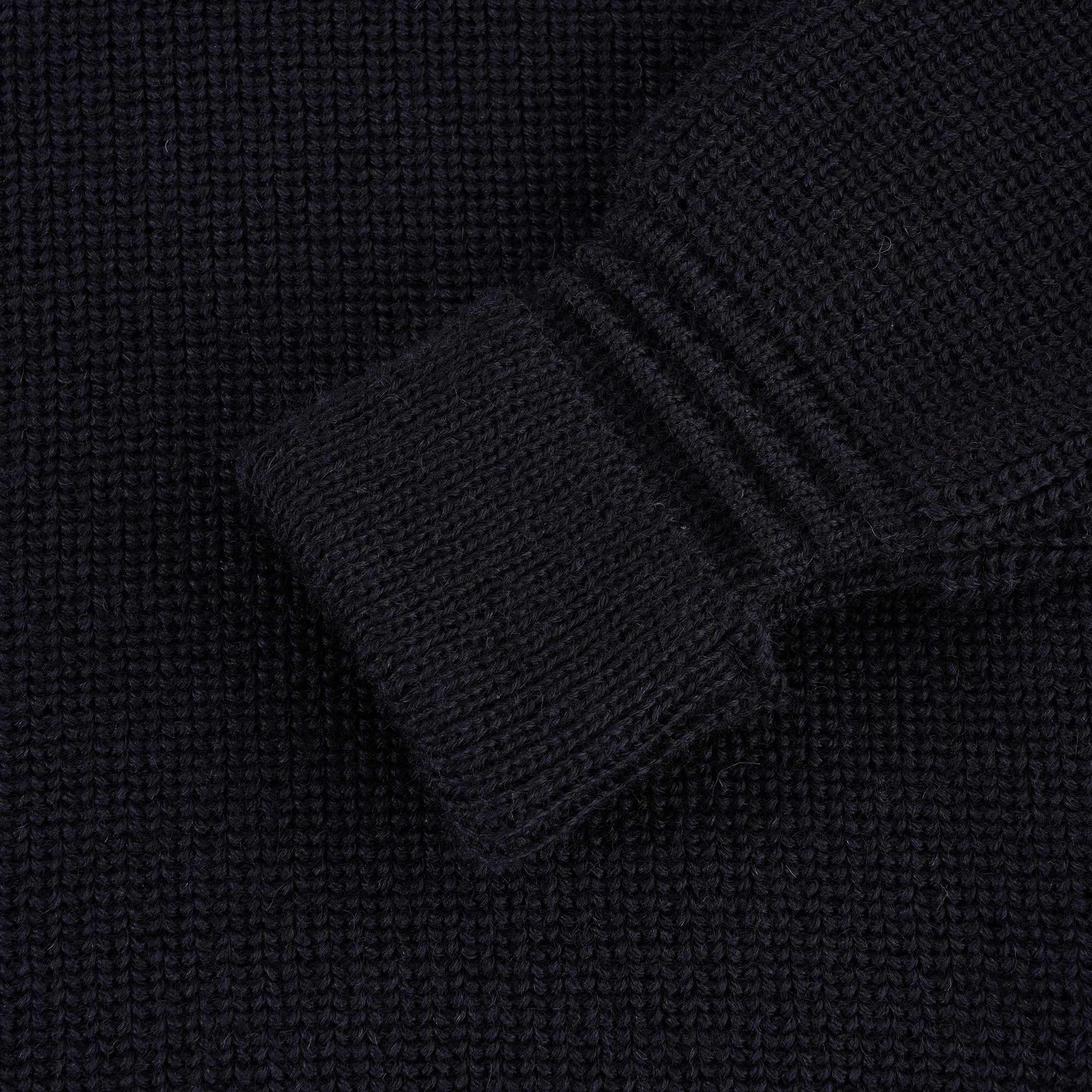 Close-up of the ribbed cuff of a navy blue jumper sleeve.