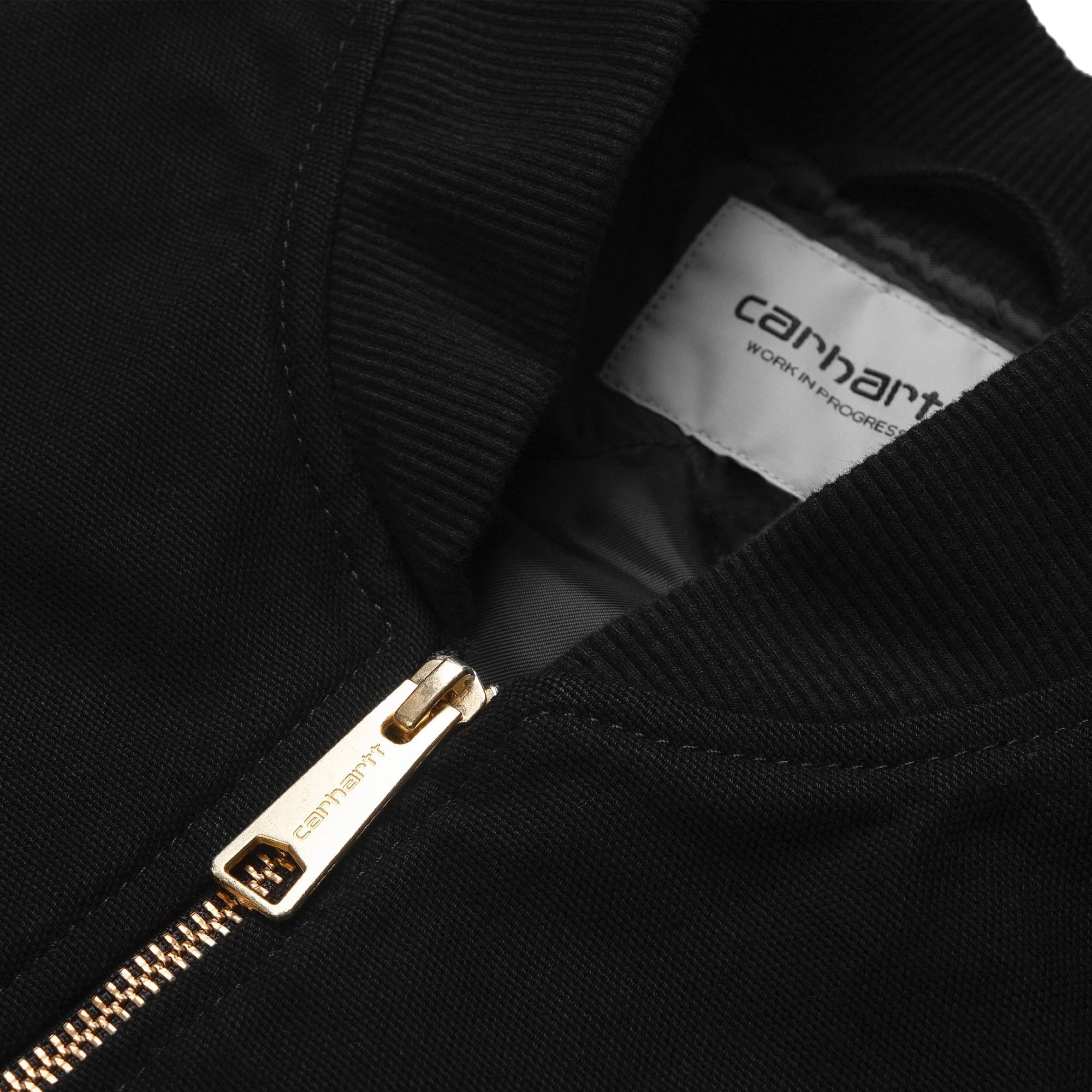 Close-up of the black Carhartt WIP vest, showing the gold zip and brand label.