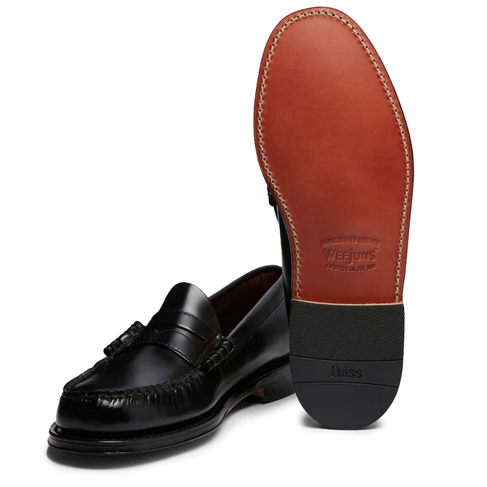A black leather Penny Loafer shoe, with one showing the sole.
